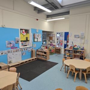 Bright classroom with blue walls and wooden tables.